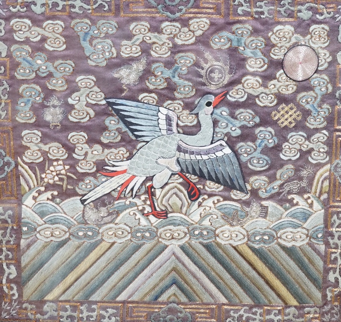 A Chinese rank badge, embroidered with multi coloured metallic and silk threads, decorated all over with auspicious symbols and a central applied Phoenix, 31.5cms wide x 29cms high